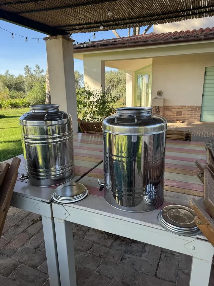Due contenitori in acciaio inox con rubinetto sul tavolo del portico
